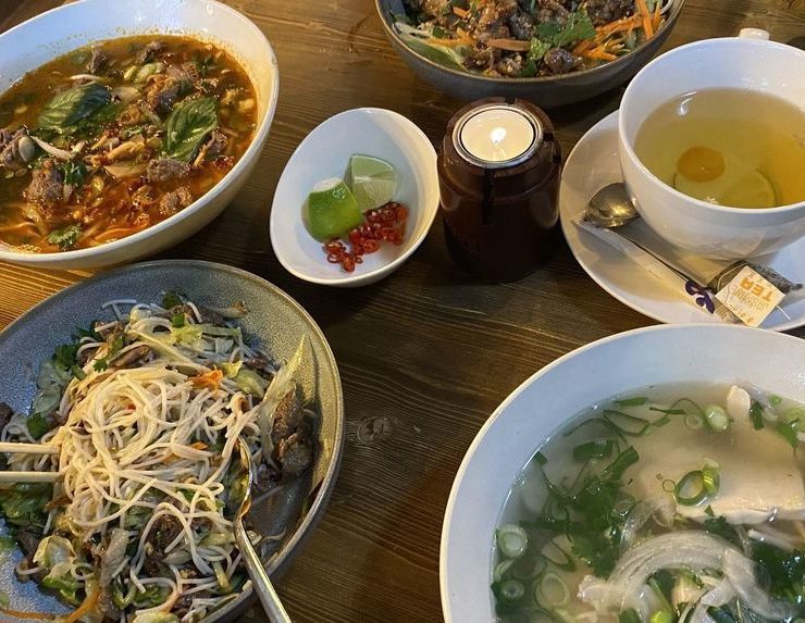 Reich gedeckter Tisch mit der Nationalspeise Pho, einer Hühnersuppe (rechts unten). © Stephan Eisner