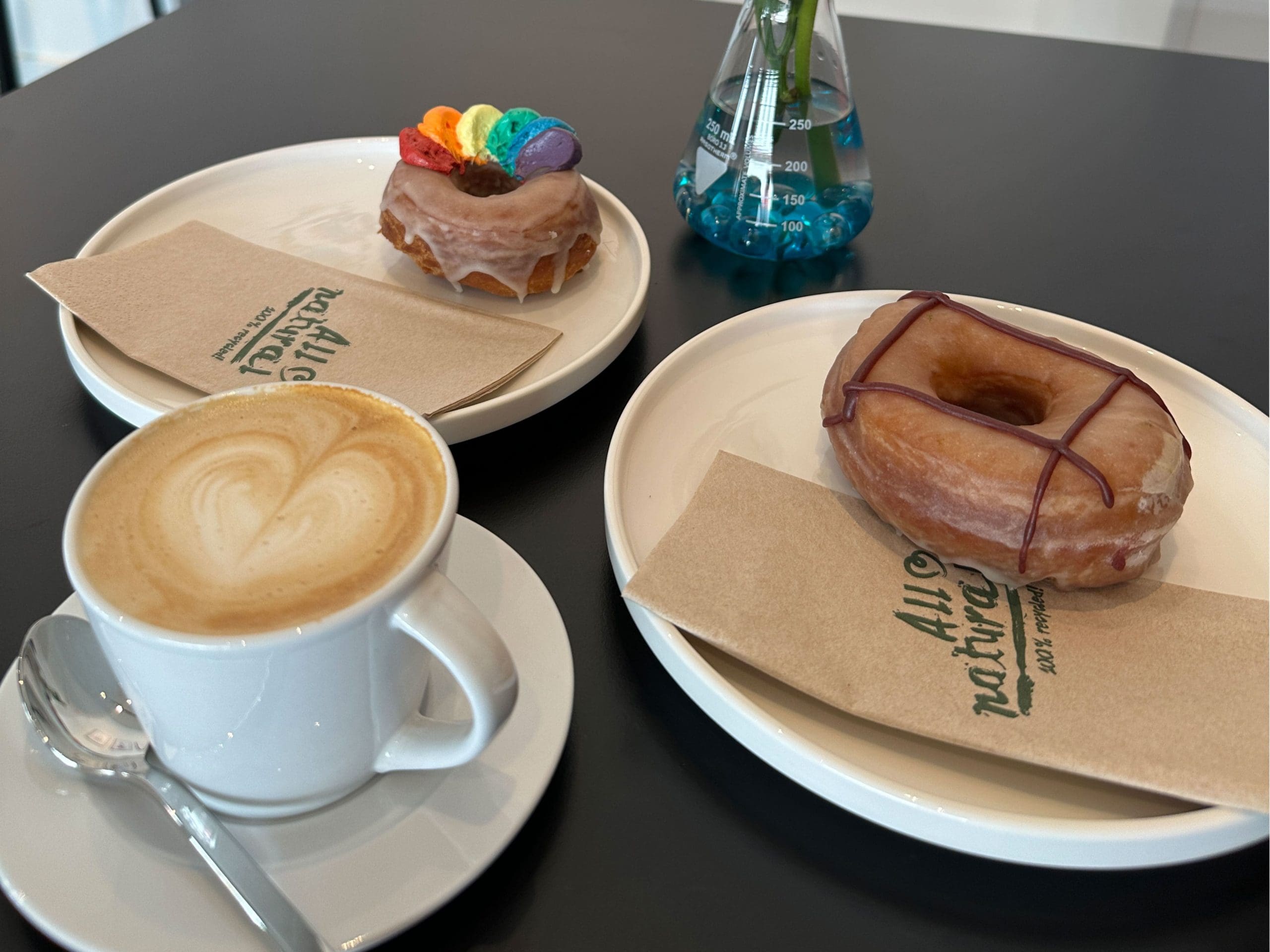 Pride Donut und Lime Açai Donut (beide vegan) und eine leckere Tasse Kaffee. © Vanessa Müller